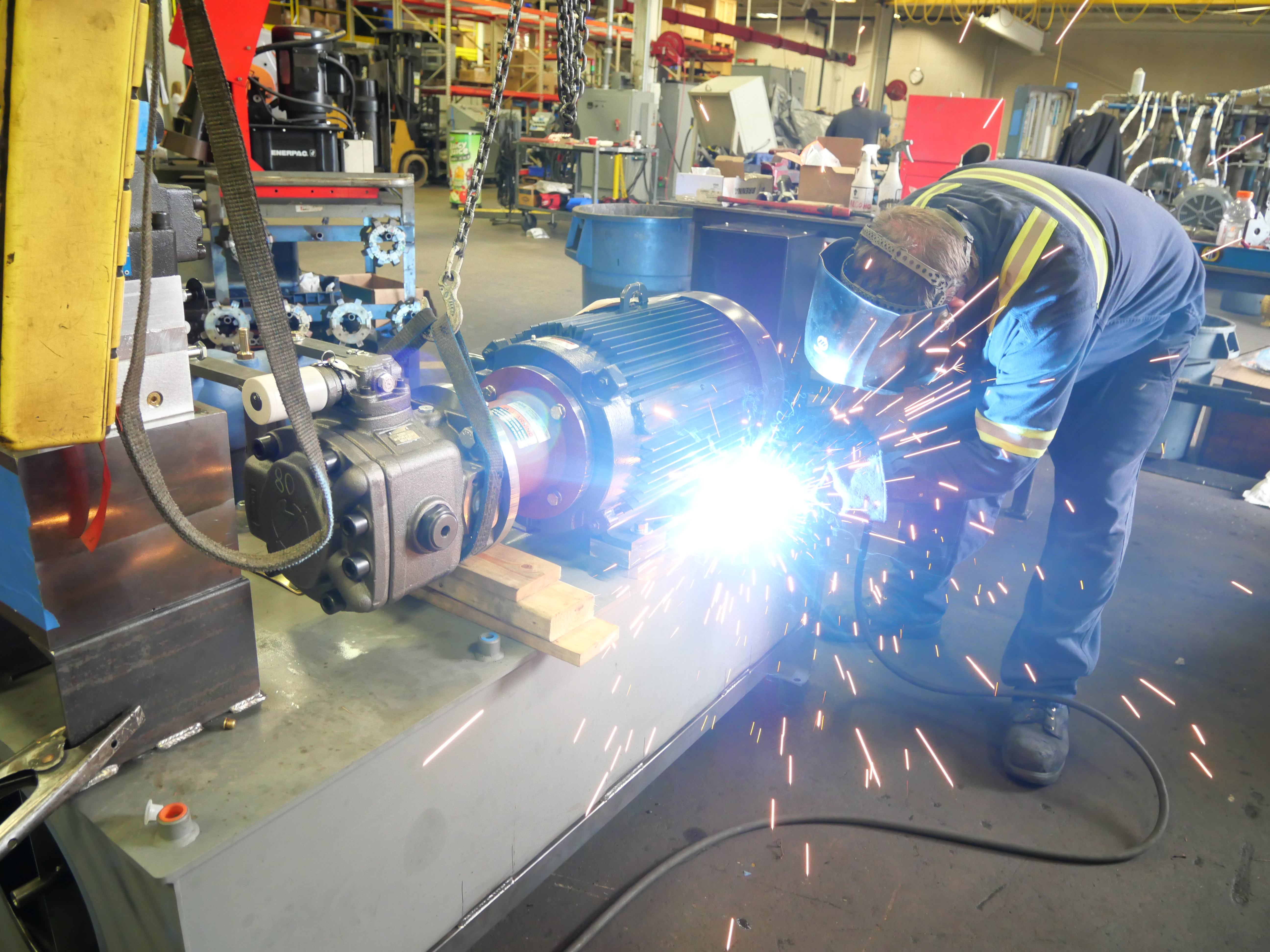 Person welding hydraulic parts to an Applied Fluid Power Green Power Unit